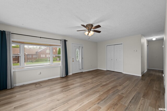 unfurnished living room featuring a ceiling fan, a textured ceiling, and light wood-style floors