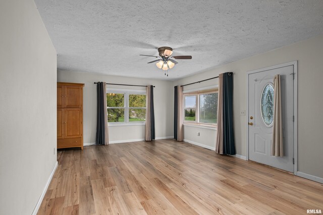 foyer featuring baseboards, a ceiling fan, light wood-type flooring, and a textured ceiling