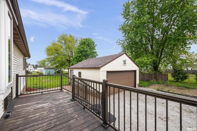 wooden terrace featuring a garage, fence, and an outbuilding