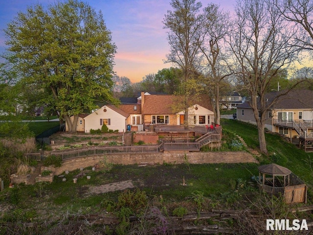 back of property at dusk with fence, a gazebo, solar panels, and a deck