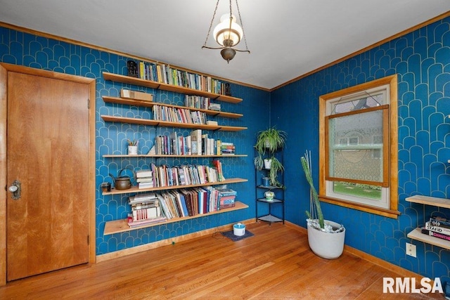 sitting room featuring crown molding, baseboards, wallpapered walls, and wood finished floors