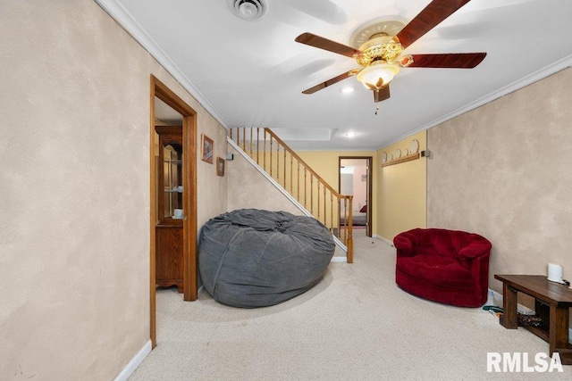 sitting room with ceiling fan, ornamental molding, baseboards, and stairway