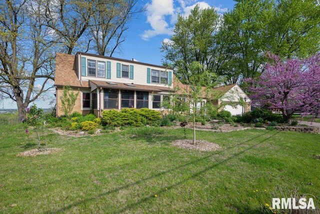 back of property with a yard, brick siding, and a sunroom