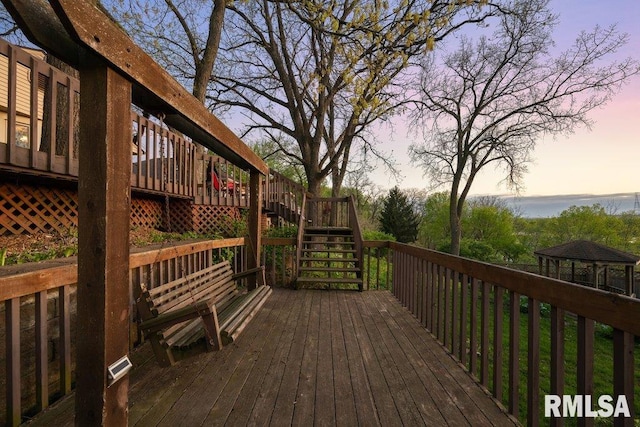deck at dusk with stairs and a gazebo