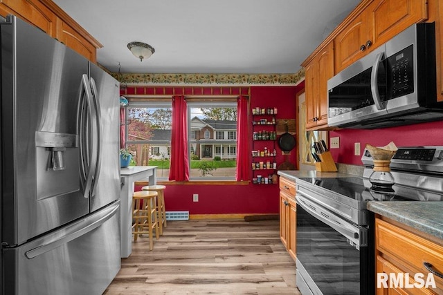 kitchen with brown cabinets, appliances with stainless steel finishes, visible vents, and light wood-style floors