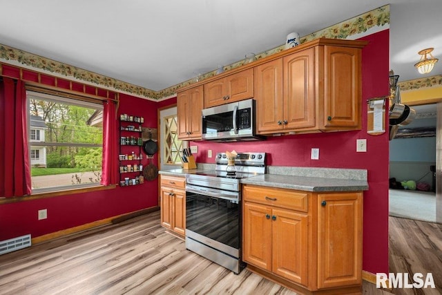 kitchen with stainless steel appliances, visible vents, brown cabinetry, and light wood-type flooring