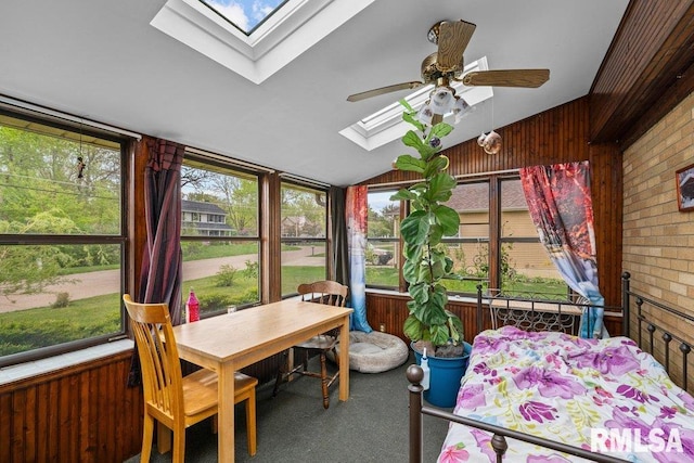 sunroom featuring outdoor dining area, a ceiling fan, carpet flooring, and wooden walls