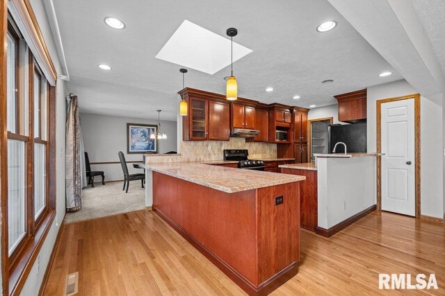 kitchen featuring freestanding refrigerator, a peninsula, a skylight, and black electric range