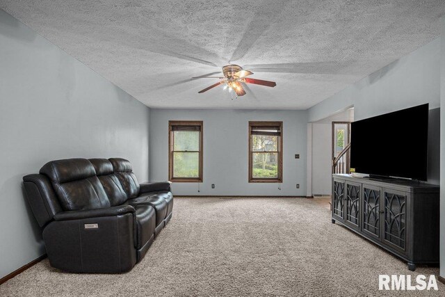 living room featuring baseboards, a ceiling fan, carpet, and a textured ceiling