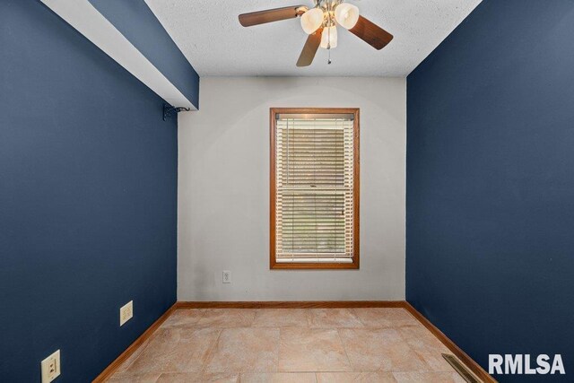 spare room with plenty of natural light, a textured ceiling, ceiling fan, and baseboards