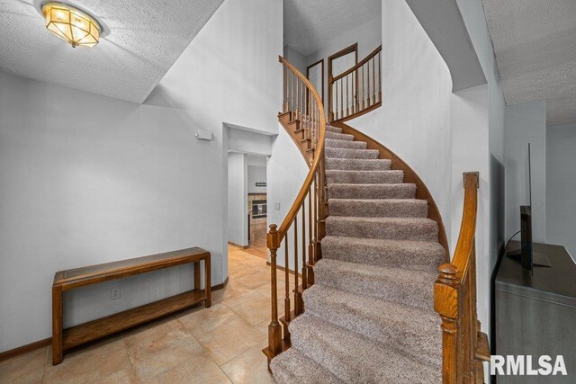 stairway with baseboards and a textured ceiling