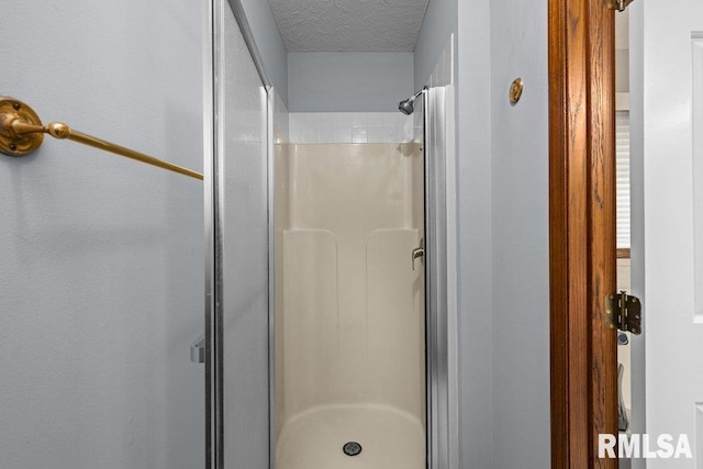 bathroom featuring a textured ceiling and a stall shower