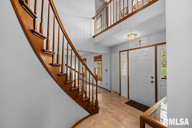 foyer entrance with plenty of natural light, stairs, and a towering ceiling