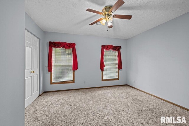 carpeted spare room featuring a healthy amount of sunlight, baseboards, ceiling fan, and a textured ceiling