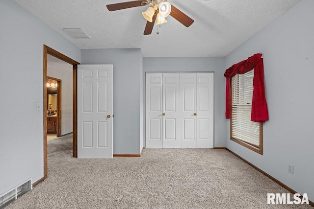 unfurnished bedroom with baseboards, carpet, a textured ceiling, and visible vents