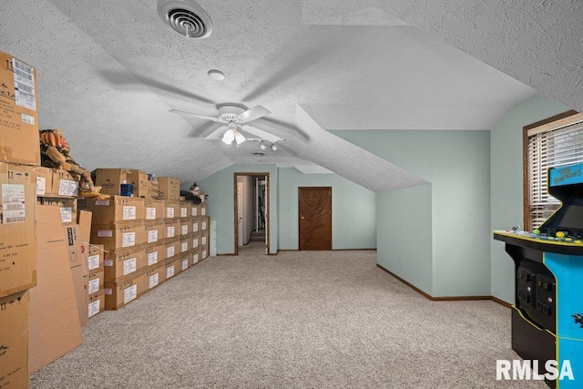 additional living space featuring visible vents, carpet floors, lofted ceiling, ceiling fan, and a textured ceiling