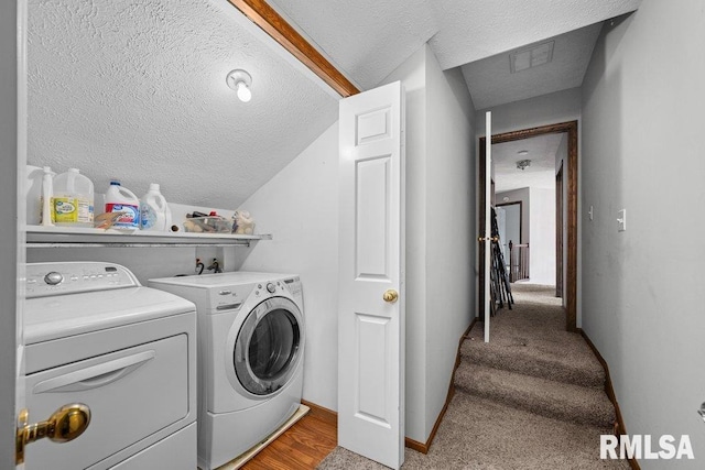 clothes washing area featuring washer and dryer, laundry area, a textured ceiling, baseboards, and visible vents