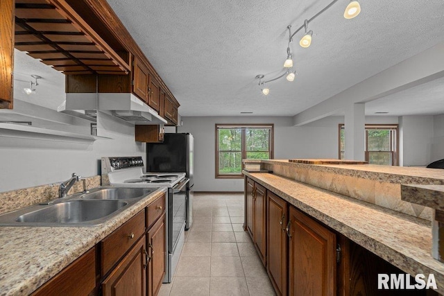 kitchen featuring electric range oven, a sink, track lighting, light tile patterned floors, and light countertops