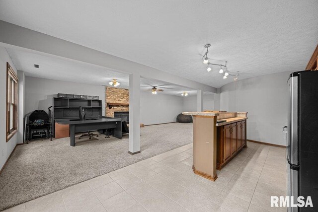 kitchen with a fireplace, light tile patterned floors, freestanding refrigerator, open floor plan, and light carpet