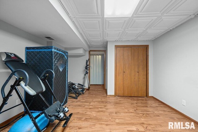 workout area featuring light wood-style floors, baseboards, an ornate ceiling, and visible vents