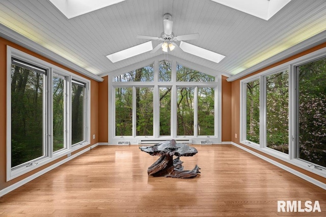 unfurnished sunroom with baseboards, visible vents, wood finished floors, and lofted ceiling with skylight