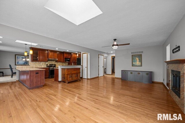 kitchen featuring appliances with stainless steel finishes, light wood-style floors, light countertops, open floor plan, and under cabinet range hood