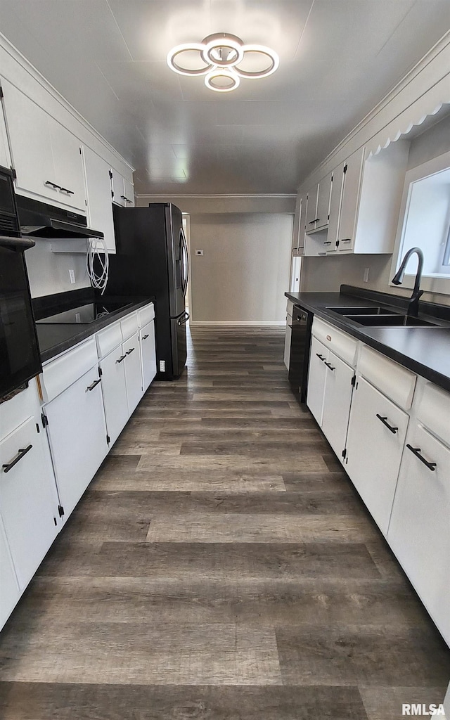 116 Ballantine St, Duquoin, IL 62832 - kitchen with dark countertops, black appliances, under cabinet range hood, and white cabinetry