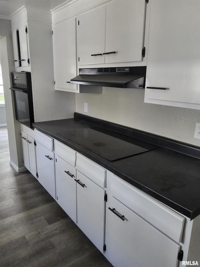 116 Ballantine St, Duquoin, IL 62832 - kitchen with under cabinet range hood, black appliances, dark countertops, dark wood-type flooring, and white cabinetry