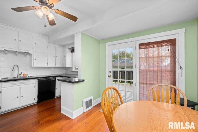 kitchen featuring black dishwasher, white cabinets, visible vents, and a sink