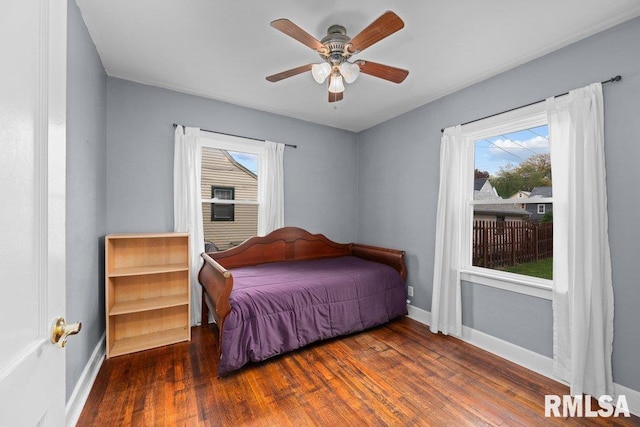bedroom with baseboards, a ceiling fan, wood finished floors, and multiple windows