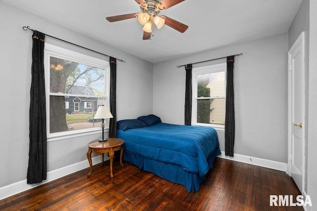 bedroom with baseboards, multiple windows, and wood finished floors