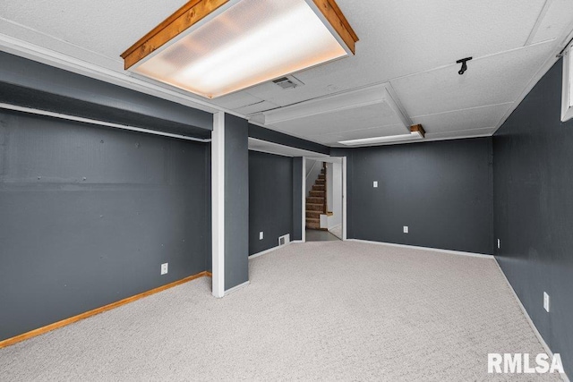finished below grade area featuring baseboards, carpet, stairs, and visible vents