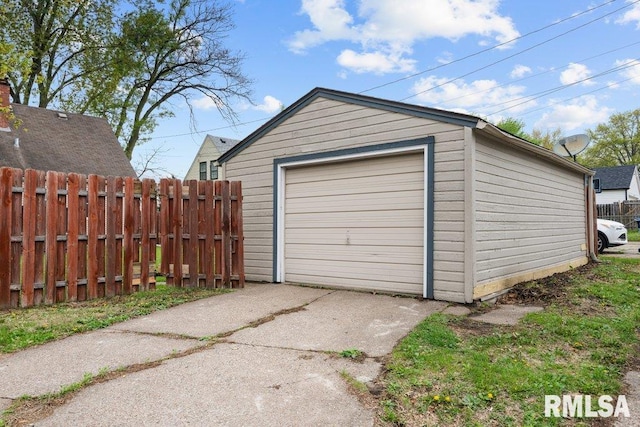 detached garage featuring fence and driveway