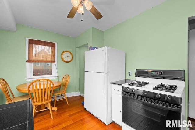 kitchen with dark countertops, light wood-style floors, range with gas stovetop, freestanding refrigerator, and a ceiling fan