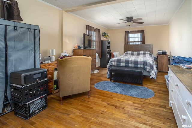 bedroom featuring a ceiling fan, ornamental molding, and wood finished floors