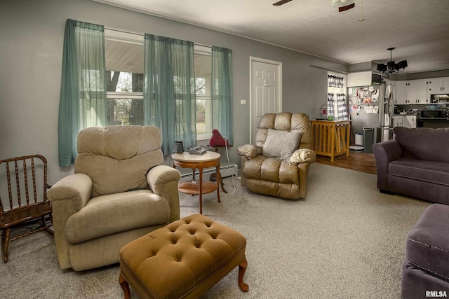 living area with ceiling fan with notable chandelier, baseboard heating, and a wealth of natural light