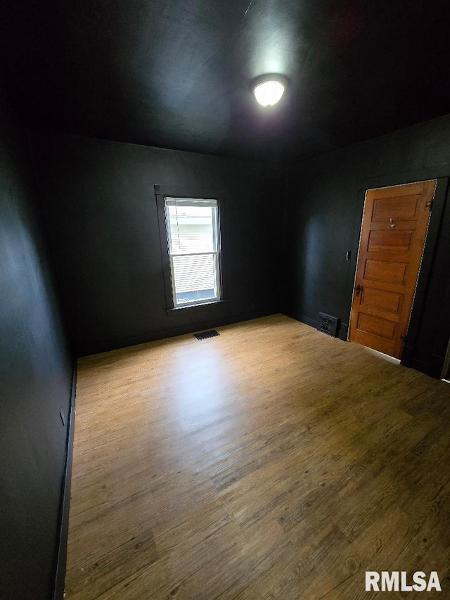 unfurnished room with wood finished floors and visible vents