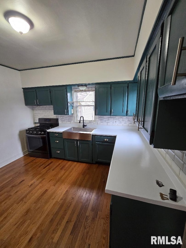 kitchen with black gas range, light countertops, tasteful backsplash, a sink, and dark wood finished floors