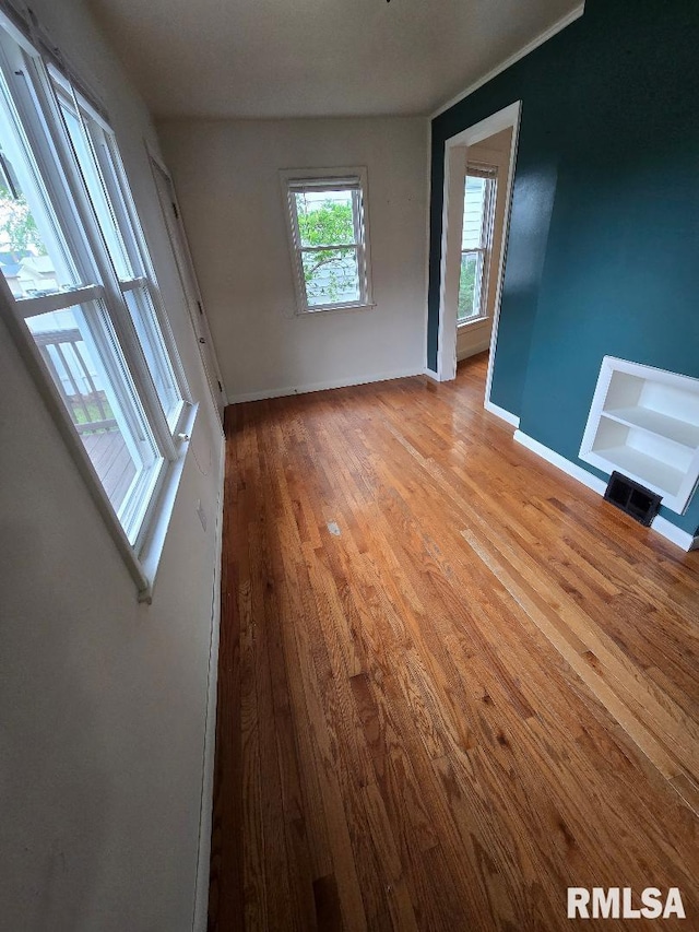 spare room with baseboards and wood finished floors