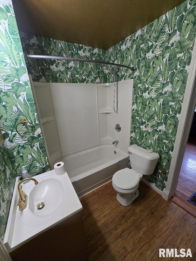 bathroom featuring wood finished floors, shower / washtub combination, vanity, toilet, and wallpapered walls
