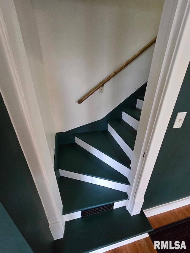 staircase with baseboards and wood finished floors