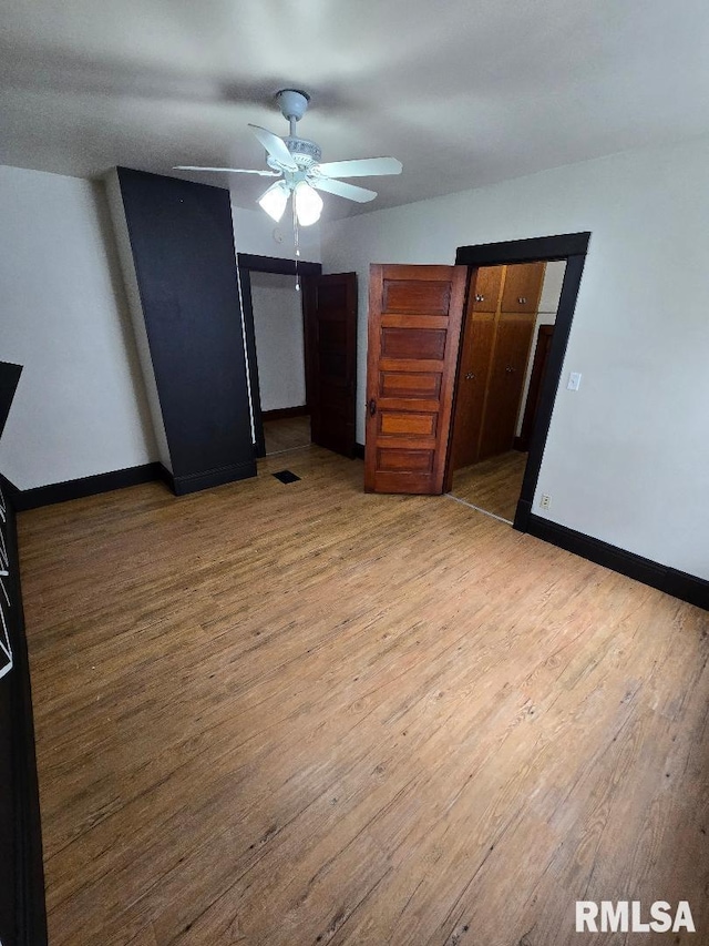 unfurnished bedroom featuring baseboards, ceiling fan, wood finished floors, and visible vents