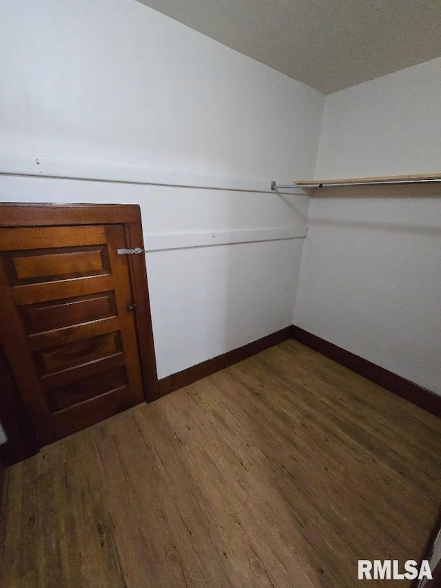 walk in closet with dark wood finished floors