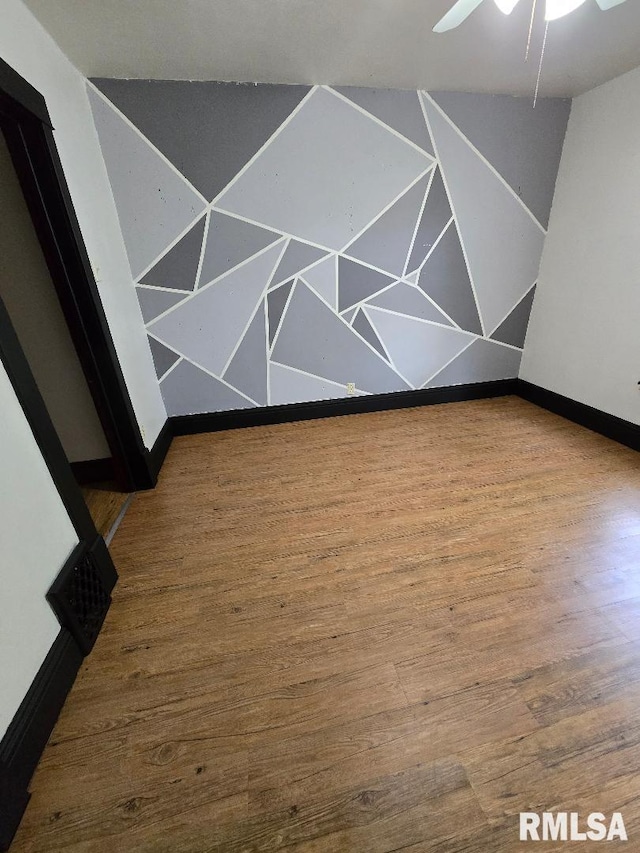 spare room with baseboards, ceiling fan, and wood finished floors