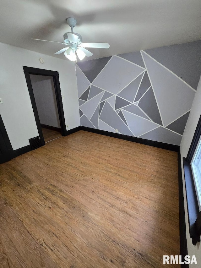 spare room featuring baseboards, ceiling fan, and wood finished floors