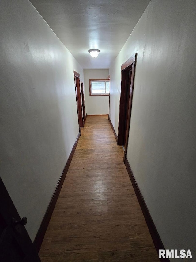 corridor with baseboards and light wood finished floors