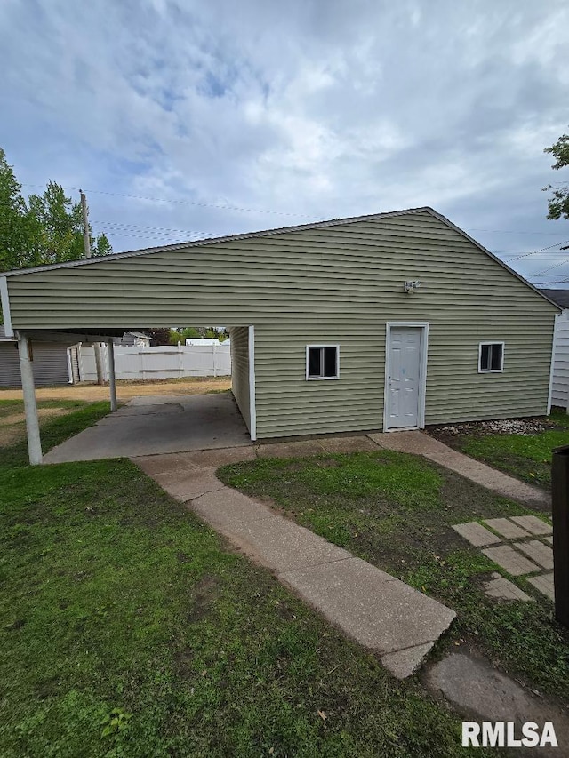 view of outdoor structure with fence and a carport