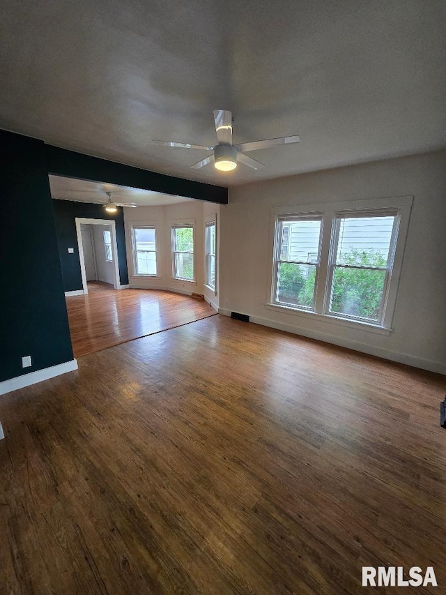unfurnished room featuring baseboards, a ceiling fan, and wood finished floors