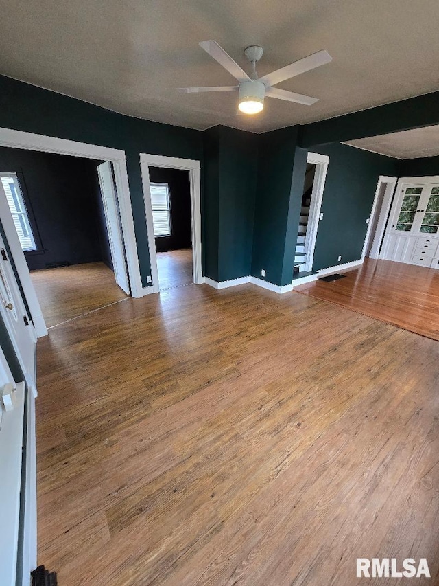 interior space with baseboards, a ceiling fan, wood finished floors, and stairway