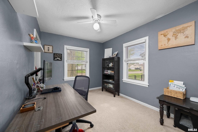office featuring baseboards, light carpet, a ceiling fan, and a textured ceiling
